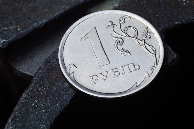 Moneda rusa denominada 1 rublo brilla sobre una superficie metálica rayada traducción del texto en la moneda quot1 rubloquot