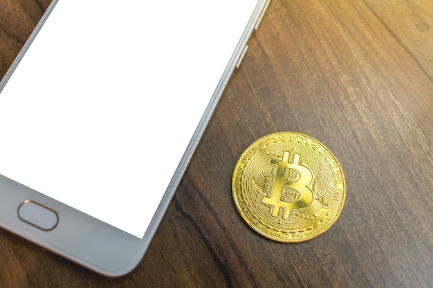 Moneda y smartphone de Bitcoin en el escritorio de madera viejo en la parte superior.