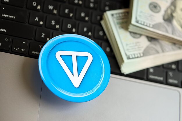 Moneda de tonelada de Telegram con una gran cantidad de billetes de cien dólares estadounidenses en la superficie de la computadora portátil