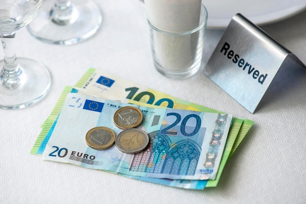 Moneda de la Unión Europea en una mesa con factura de recibo plato de copas de vino en un restaurante en Europa