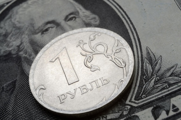 Una moneda con un valor nominal de 1 rublo se encuentra en un billete del primer plano del dólar estadounidense