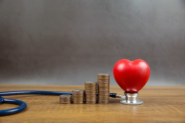 Monedas apiladas en forma de gráfico y corazón con estetoscopio. Conceptos un examen físico para el cuidado de la salud y el seguro médico.