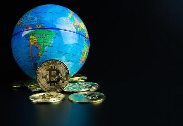 Monedas Bitcoin colocadas delante de un mundo modelo sobre un fondo negro