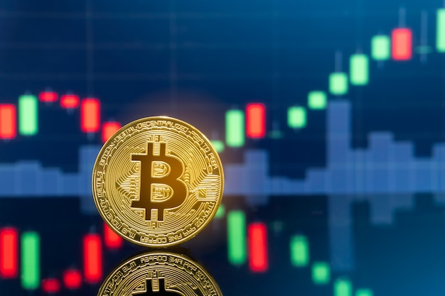 Monedas de Bitcoin de metal físico con gráfico de precios de mercado de intercambio de comercio global en el fondo.