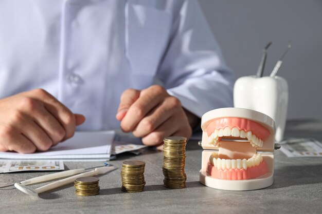 Monedas decorativas de mandíbula y dentista sobre fondo gris