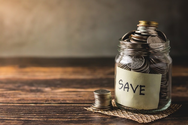 Monedas de depósito de ahorros en una botella de vidrio transparente