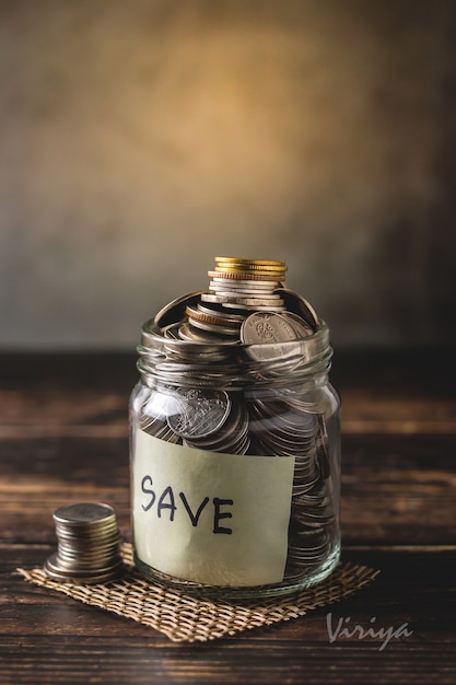 Monedas de depósito de ahorros en una botella de vidrio transparente