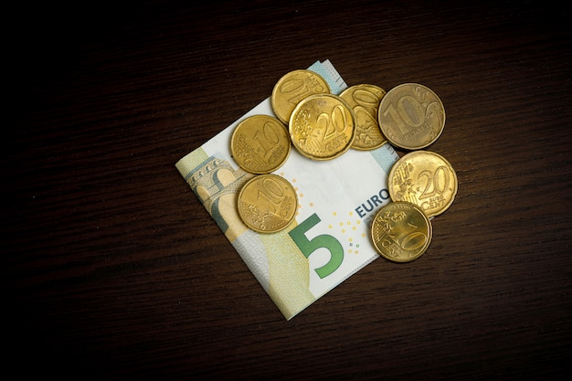 Monedas en euros en la pared de la mesa de madera oscura