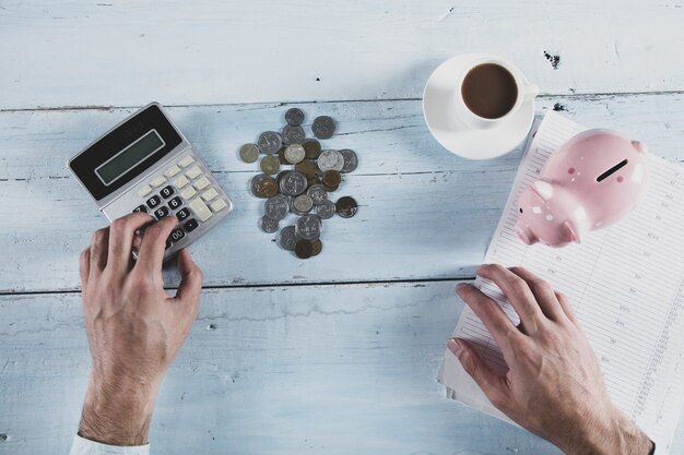 Monedas de mano de hombre y hucha con calculadora sobre la mesa