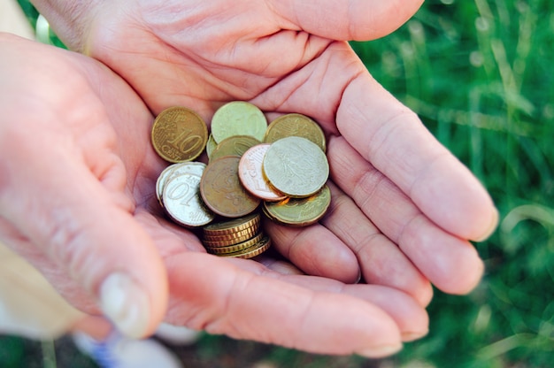 Monedas en manos de la abuela de edad cerca