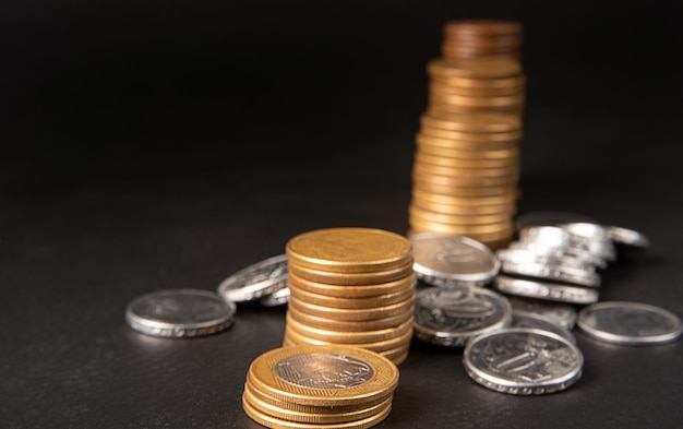 Monedas, monedas brasileñas de diversos valores apiladas en cuero negro, enfoque selectivo.