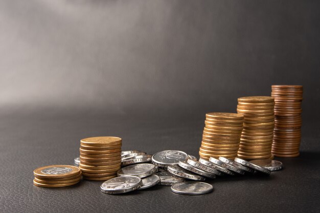 Monedas, monedas brasileñas de diversos valores apiladas en cuero negro, enfoque selectivo.