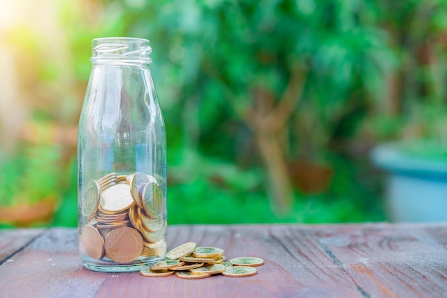 Monedas de oro en botella sobre fondo de madera concepto de ahorro de dinero