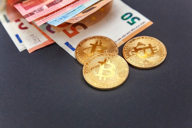 Monedas de oro simbólicas de bitcoins en billetes en euros