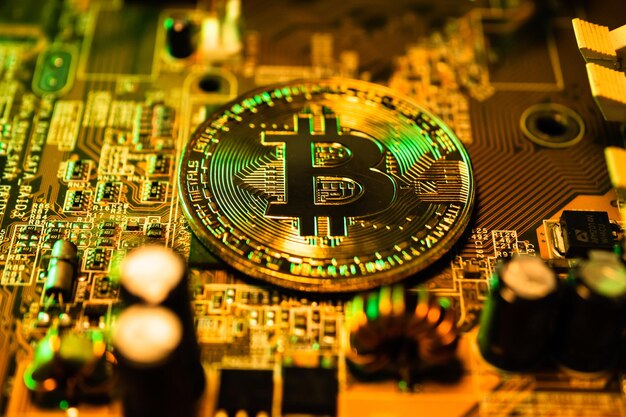 Monedas de oro con símbolo de bitcoin en una computadora de placa principal