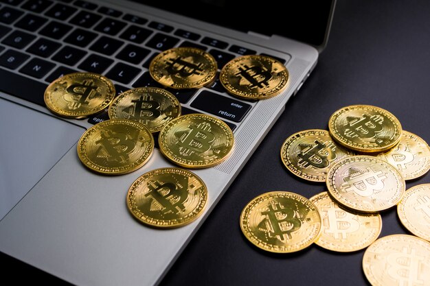 Monedas de oro con el símbolo de bitcoin en el teclado de la computadora y un fondo negro.