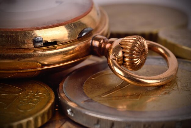 Monedas y reloj de bolsillo dorado.