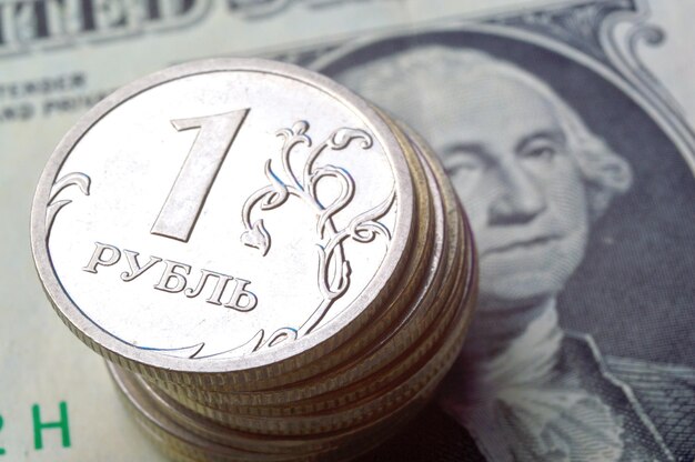 Las monedas rusas de 1 rublo yacen en un billete de 1 dólar americano