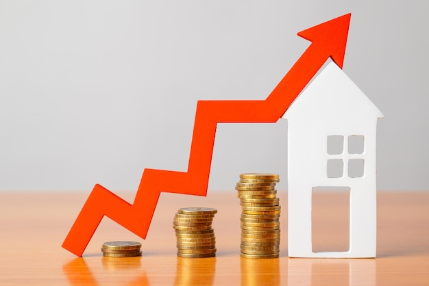 Monedas sobre una mesa una flecha roja hacia arriba y albergan el concepto del aumento del precio de los bienes raíces