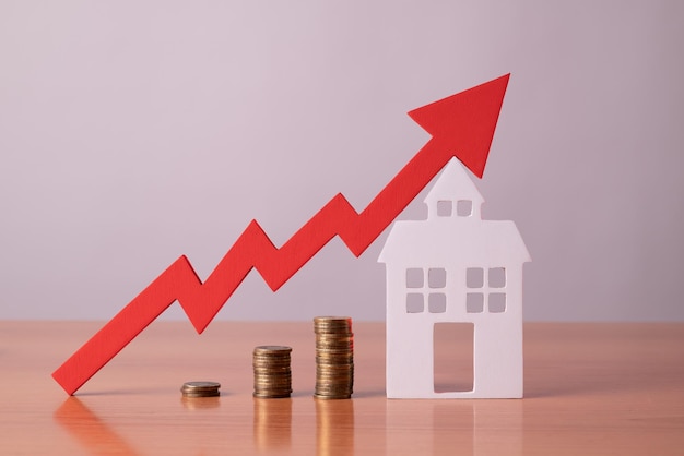 Monedas sobre una mesa una flecha roja hacia arriba y albergan el concepto del aumento del precio de los bienes raíces