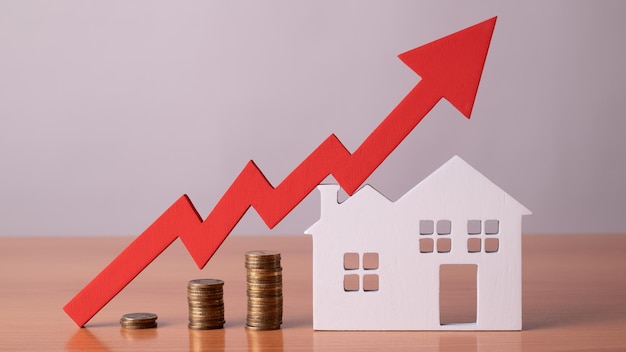 Monedas sobre una mesa una flecha roja hacia arriba y albergan el concepto del aumento del precio de los bienes raíces