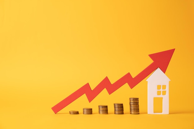 Monedas sobre una mesa una flecha roja hacia arriba y albergan el concepto del aumento del precio de los bienes raíces