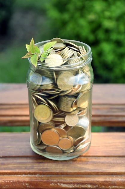 Monedas en tarro de dinero en la mesa al aire libre