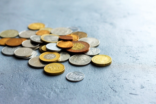 Monedas viejas de diversos países en un fondo concreto gris.