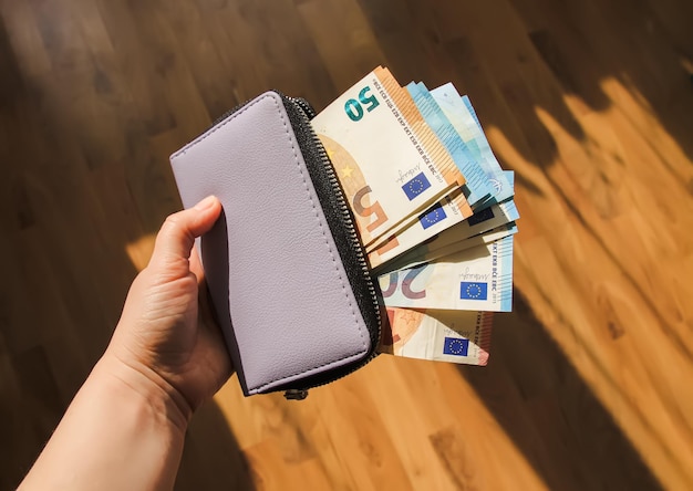 Monedero con billetes de dinero en euros en una mano