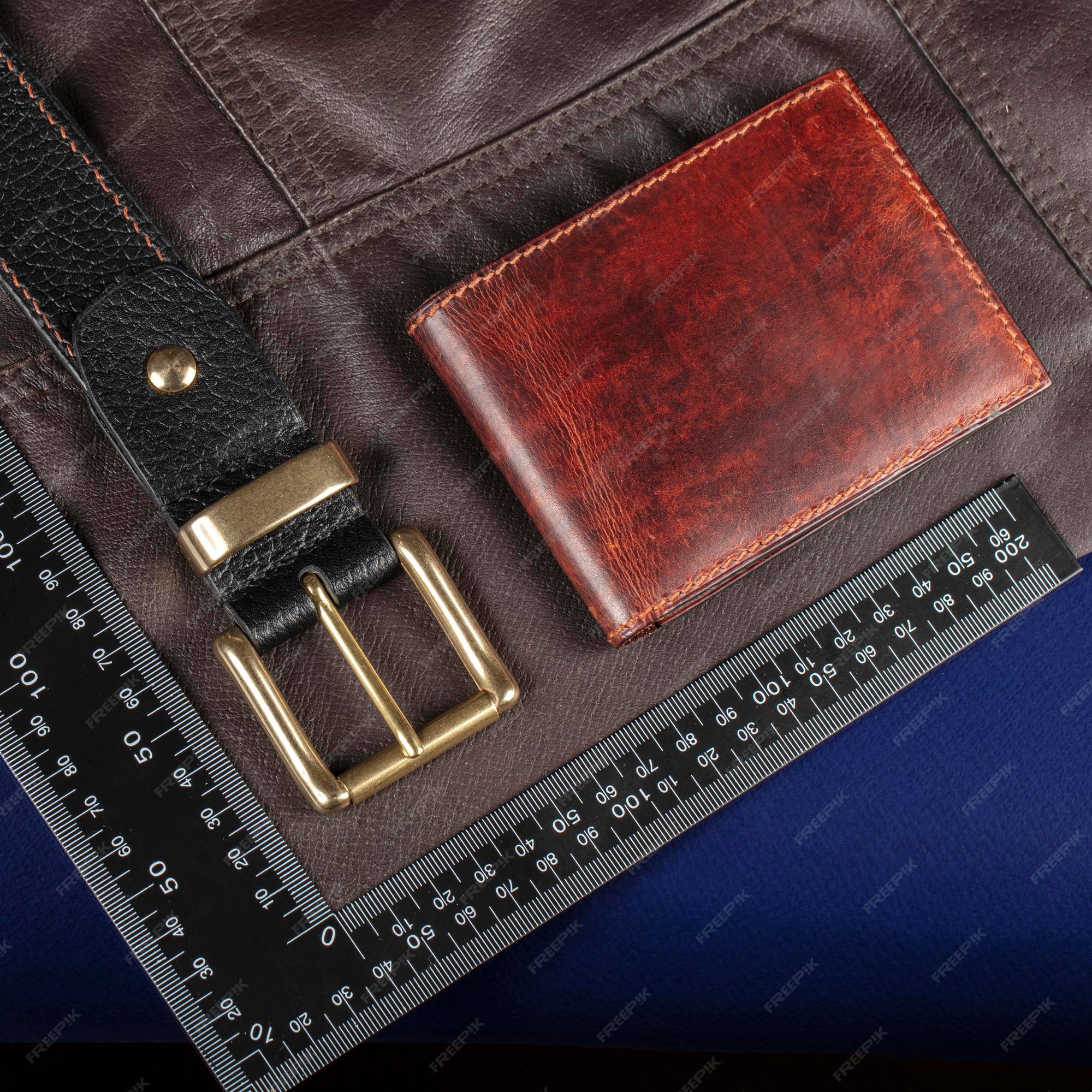Monedero y cinturón de artículos de cuero contra el fondo de una regla para cortar y coser | Premium