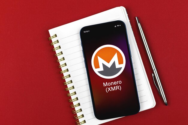 Monero XMR-Symbol. Handel mit Kryptowährung, digitalem und virtuellem Geld, Banking mit Mobiltelefonkonzept. Business-Arbeitsplatz, Foto mit Tischansicht