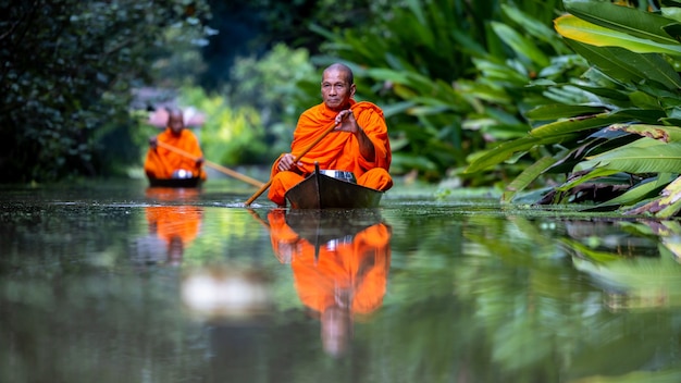 Monge budista em um pequeno barco de madeira navegando no canal