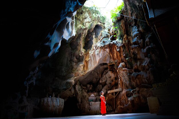 Foto monge olhando para longe enquanto está de pé na caverna