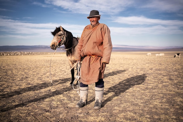 Mongolischer Hirte in traditioneller Kleidung mit Pferd in der Steppe der Mongolei