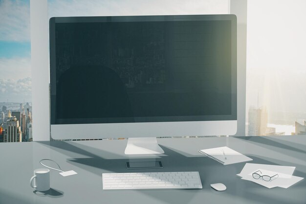 Monitor de computadora en blanco con vasos de café y otros accesorios sobre la mesa