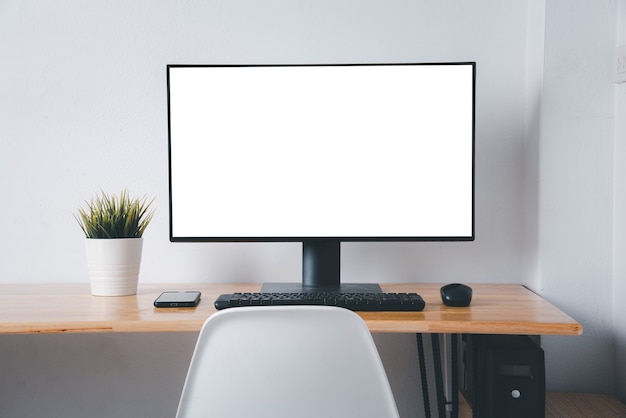 Monitor de computador com tela branca em branco na mesa de trabalho com teclado de mouse sem fio