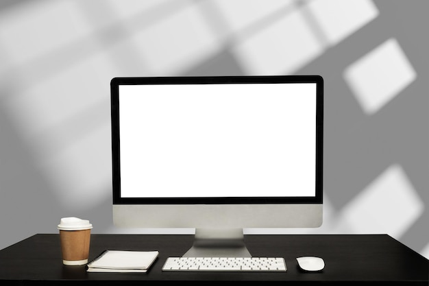 Monitor de computador com tela em branco branca colocando na mesa de trabalho branca com mouse sem fio e teclado sobre escritório moderno desfocado como backgroundxA