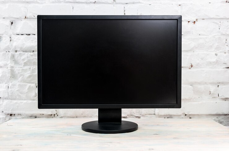 Foto monitor de computador em uma mesa contra parede de tijolo branco tela preta em branco