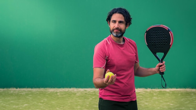 Monitor de padel segurando raquete preta com bola de tênis amarela na mão