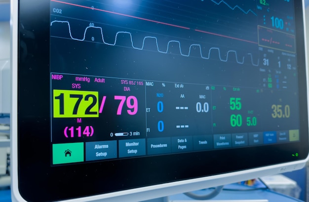 Monitor hospitalario que muestra signos vitales, frecuencia cardíaca, presión arterial, temperatura y oximetría de pulso.