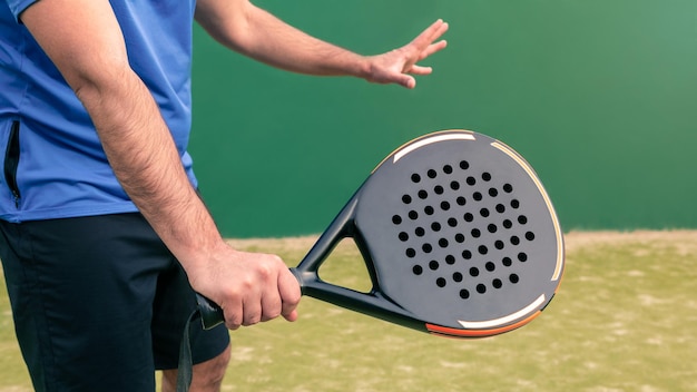 Monitor practicando deporte de pádel con una raqueta de pádel negra sobre un césped verde