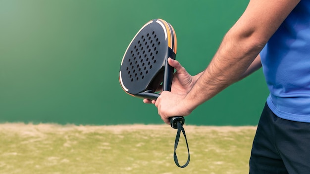 Foto monitor profissional de padel segurando raquete preta na quadra verde conceito de jogo