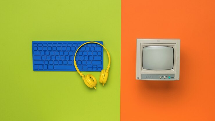 Foto monitor vintage y teclado azul sobre un fondo naranja. equipo retro. endecha plana.