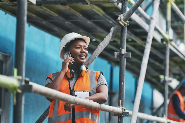 Monitoramento da concepção e execução de uma nova construção Foto de uma jovem falando ao celular enquanto trabalhava em um canteiro de obras