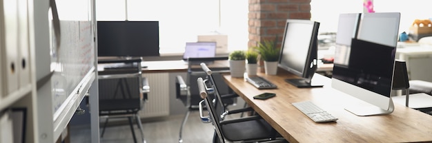 Monitores de computadora de pie sobre la mesa en la oficina vacía. Concepto de lugar de trabajo convenientemente equipado