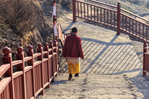 Monja budista caminando por la escalera en Larung gar en un momento cálido y con niebla por la mañana, Sichuan