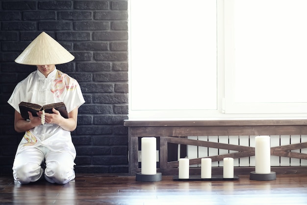 Monje asiático en kimono leyendo un libro viejo