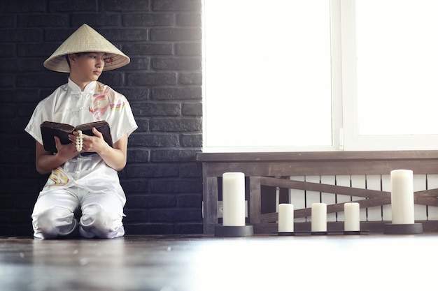 Monje asiático en kimono leyendo un libro viejo