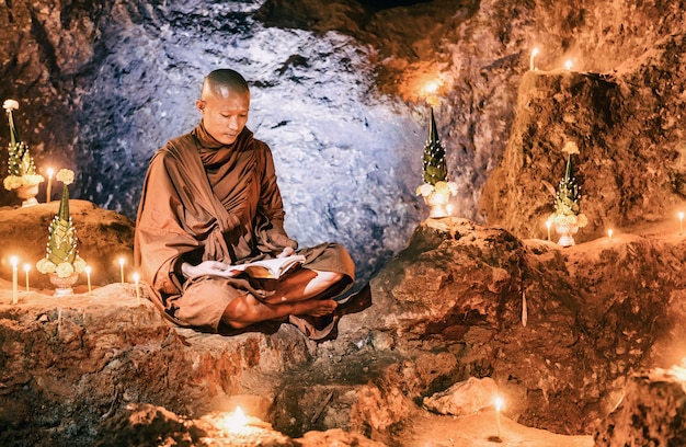 Monje leyendo libro dentro de la cueva, Tailandia