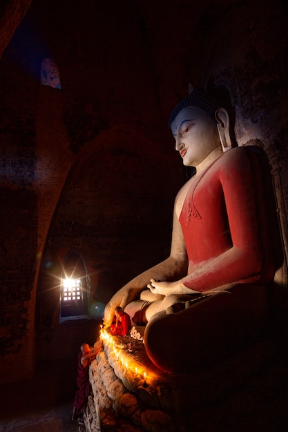 Monjes rezando a la estatua de Buda con velas